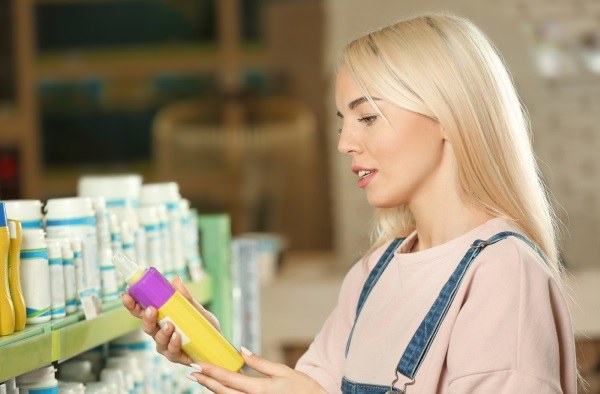 Person reading the label on a shampoo bottle before buying